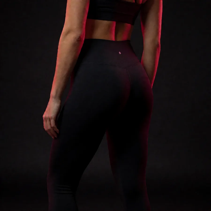 Silueta femenina de espaldas con ropa deportiva negra, glúteos y piernas tonificados