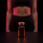 Vial de vidrio ámbar con tapa naranja sobre superficie negra reflectante con luz roja